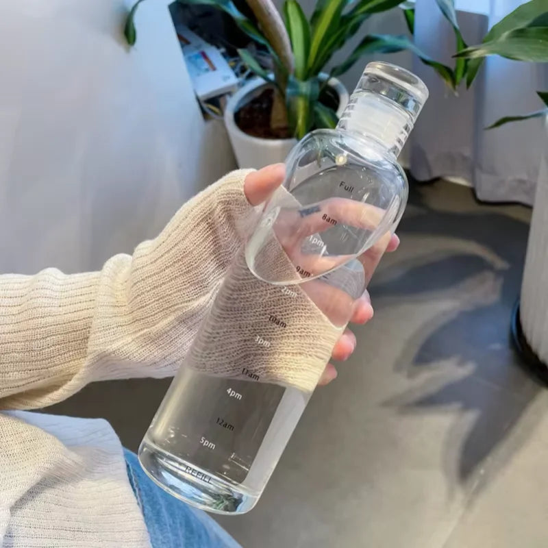 Hand holding a clear hydration tracker water bottle with time markings